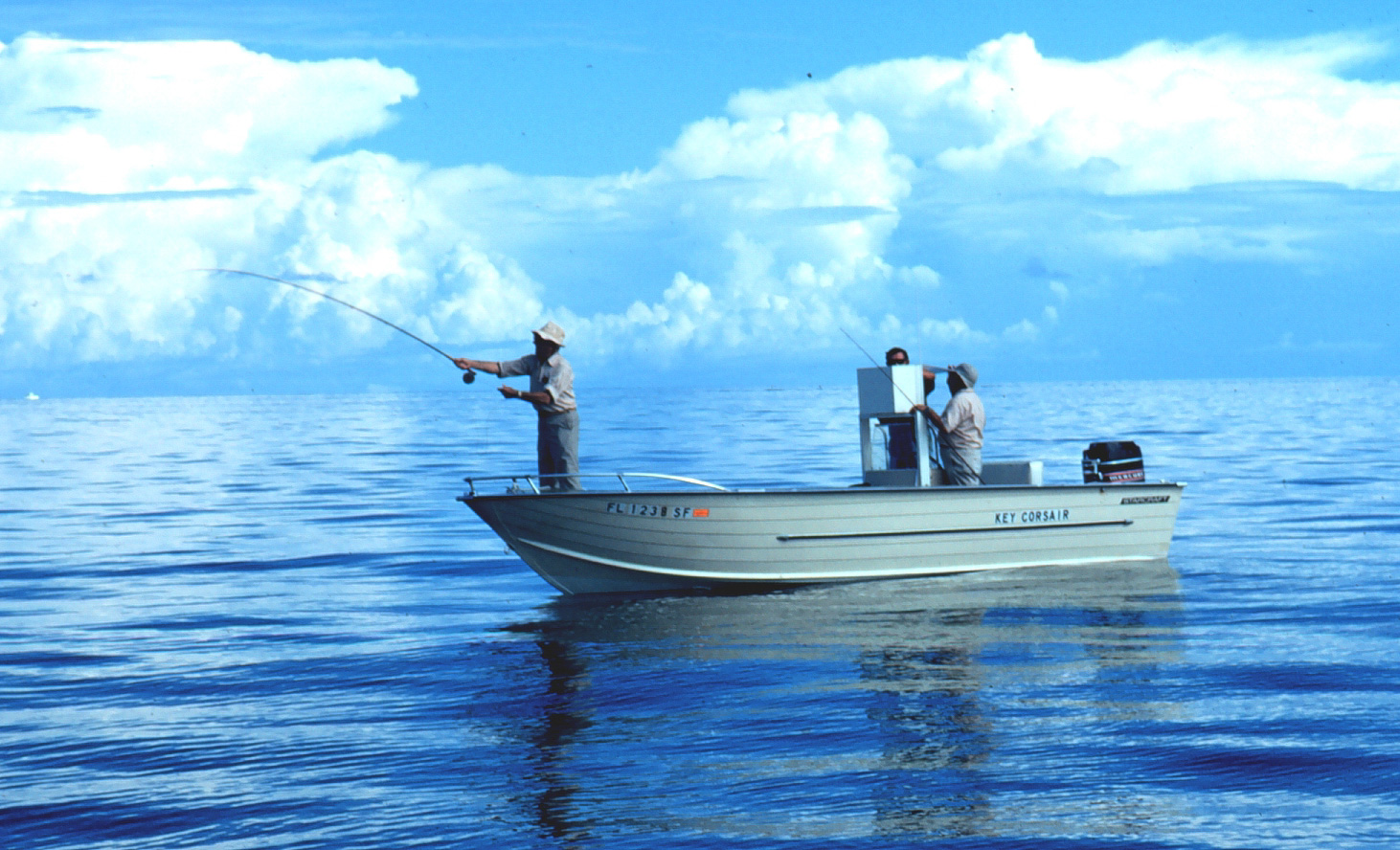 three men in fishing boat with one casting